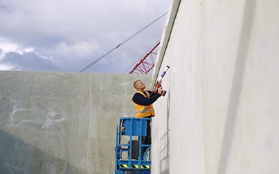 Construction worker in a construction environment applying Sabre adhesive