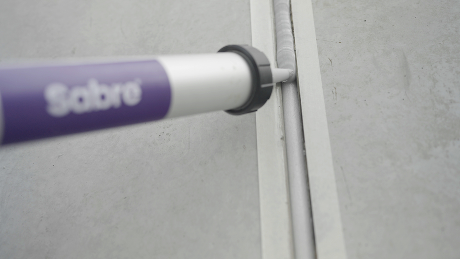close-up of sausage gun dispensing into joint with backer rod visible